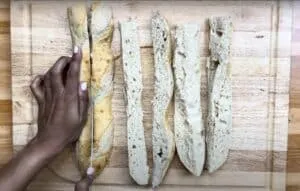Slicing a baguette on a wooden board, revealing the soft interior for bread preparation or recipe ideas.